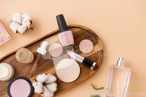 Image of makeup, perfume and cosmetics on wooden tray