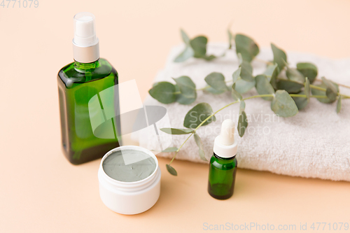 Image of serum, clay mask, oil and eucalyptus on bath towel