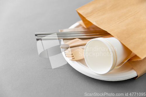 Image of wooden forks, knives and paper cups on plate