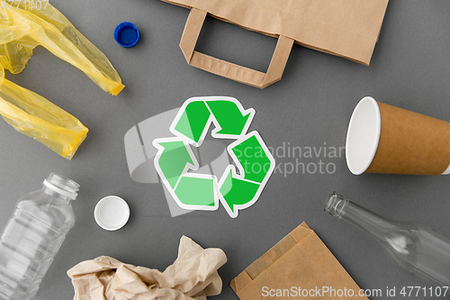 Image of green recycle symbol with household waste on grey
