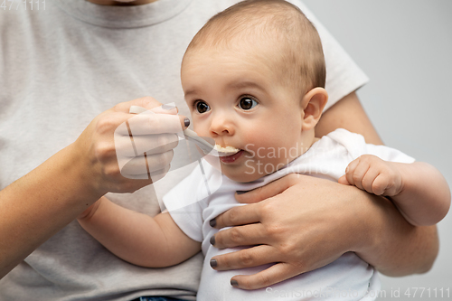 Image of close up of mother with spoon feeding little baby