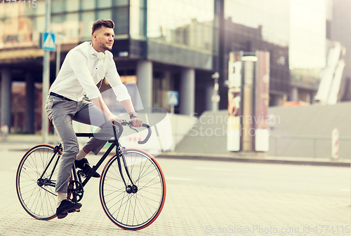 Image of man with headphones riding bicycle on city street