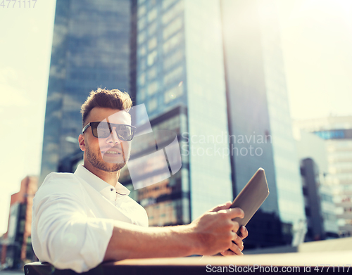 Image of man with tablet pc sitting on city street bench