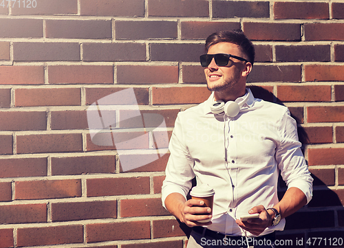 Image of man with smartphone and coffee cup on city street