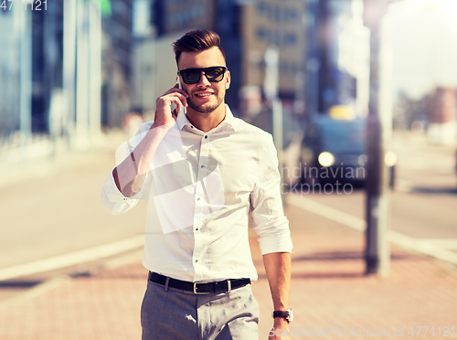 Image of happy man with smartphone calling on city street