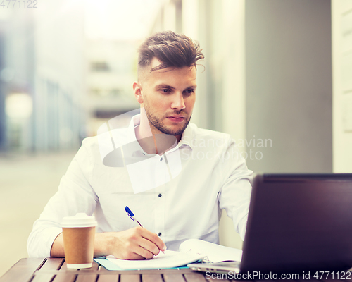 Image of man with laptop and coffee at city cafe