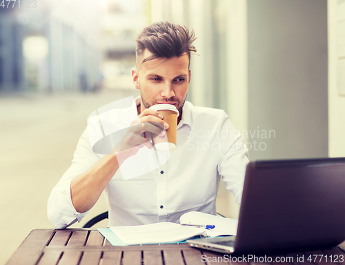 Image of man with laptop and coffee at city cafe