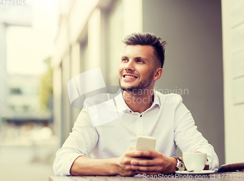 Image of man with smartphone and coffee at city cafe