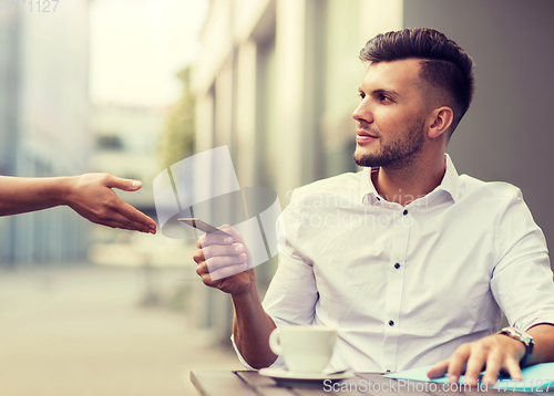 Image of man with credit card paying for coffee at cafe