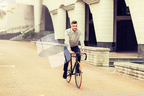 Image of young man riding bicycle on city street