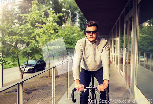 Image of young man riding bicycle on city street