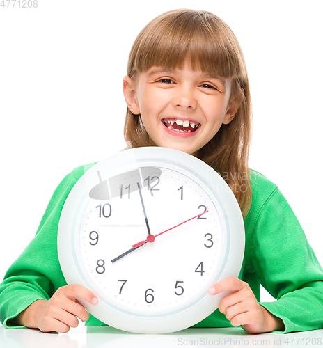 Image of Little girl is holding big clock