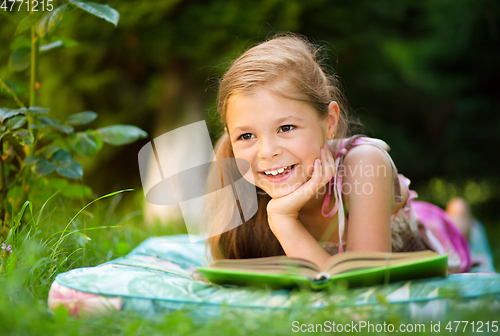 Image of Little girl is reading a book outdoors