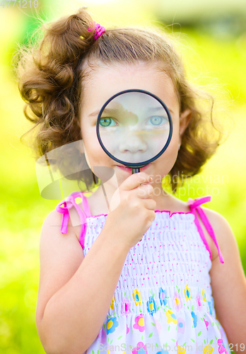 Image of Little girl is looking through magnifier
