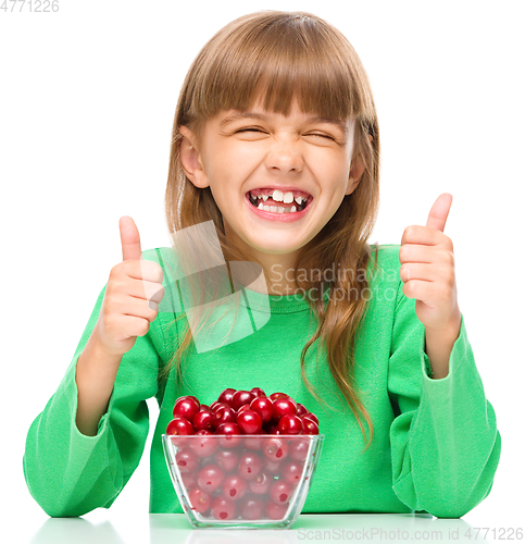 Image of Cute girl is eating cherries showing thumb up sigh