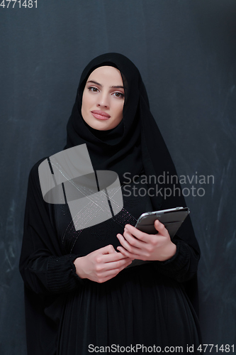 Image of Young Arab businesswoman in traditional clothes or abaya with tablet computer