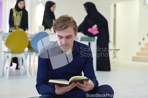 Image of Young muslim man reading Quran during Ramadan