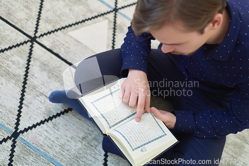 Image of Young muslim man reading Quran during Ramadan
