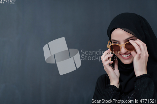 Image of Young muslim businesswoman in traditional clothes or abaya using smartphone