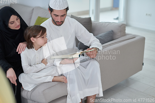 Image of Young muslim family reading Quran during Ramadan