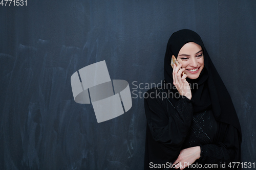 Image of Young muslim businesswoman in traditional clothes or abaya using smartphone