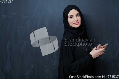 Image of Young muslim businesswoman in traditional clothes or abaya using smartphone