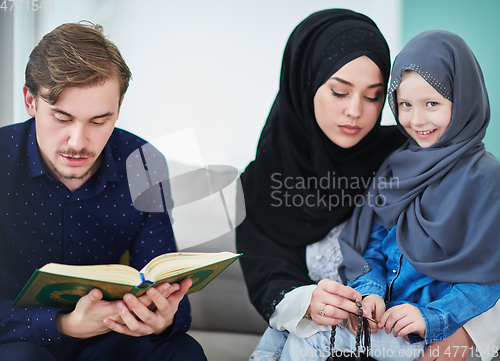 Image of Young muslim family reading Quran during Ramadan