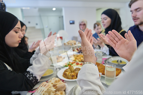 Image of Muslim family making iftar dua to break fasting during Ramadan.