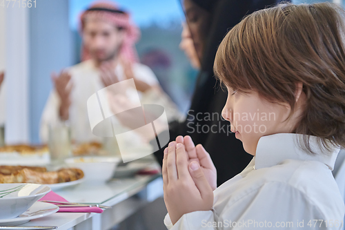Image of Muslim family making iftar dua to break fasting during Ramadan.