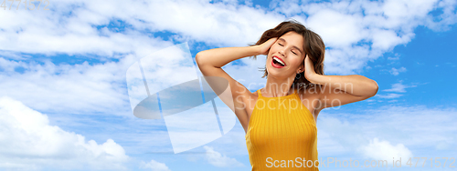 Image of happy laughing young woman in yellow top over sky