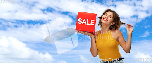 Image of happy smiling young woman posing with sale sign