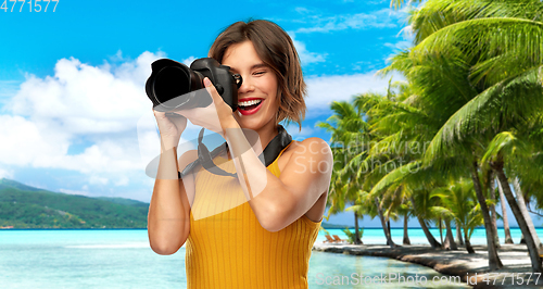 Image of happy woman photographer with camera on beach