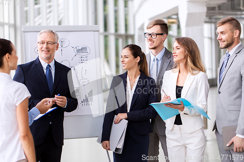 Image of business team with scheme on flip chart at office