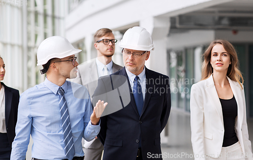 Image of business team in helmets walking along office