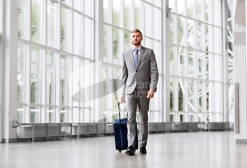 Image of businessman with travel bag walking along office