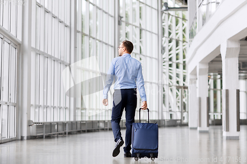 Image of businessman with travel bag walking along office