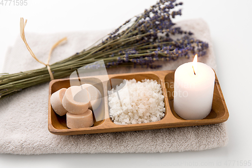 Image of sea salt, soap, candle and lavender on bath towel