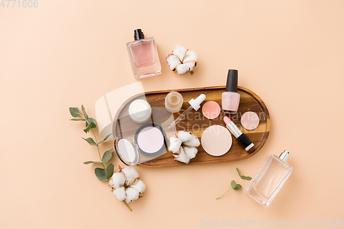 Image of makeup, perfume and cosmetics on wooden tray