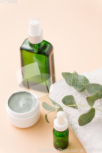 Image of serum, clay mask, oil and eucalyptus on bath towel