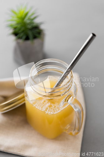 Image of glass mug of juice and reusable metallic straw