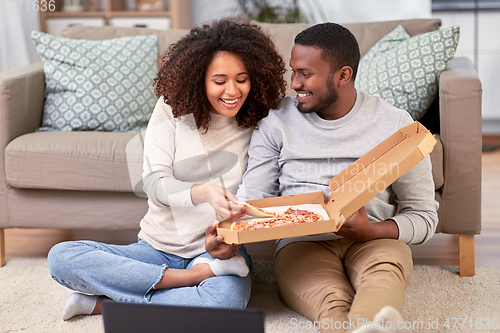 Image of happy african american couple eating pizza at home