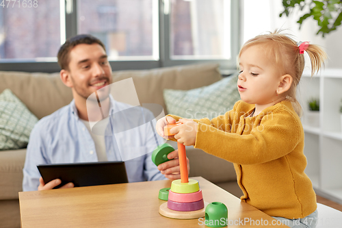Image of father with tablet pc and baby daughter at home