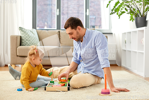 Image of father playing with little baby daughter at home