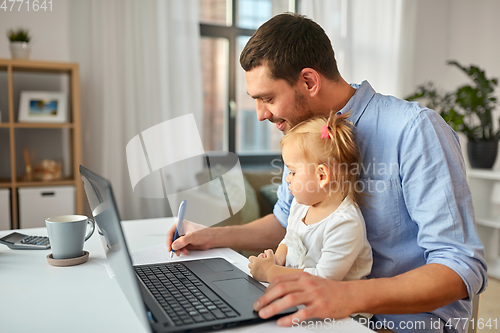 Image of working father with baby daughter at home office