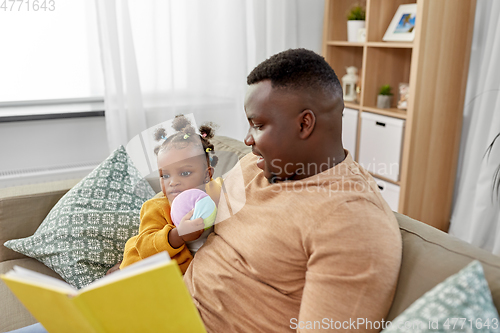 Image of african father reading book for baby daughter