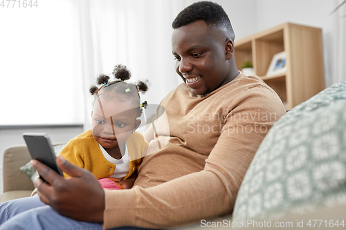 Image of father with smartphone and baby daughter at home