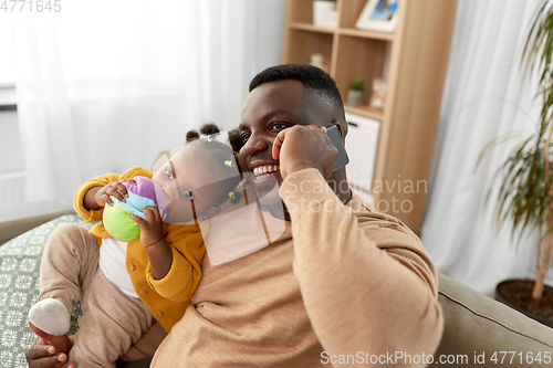 Image of father with baby at home calling on smartphone