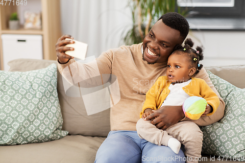 Image of happy father with baby taking selfie at home
