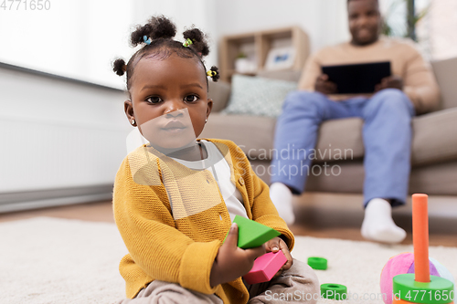 Image of african baby girl playing with toy blocks at home