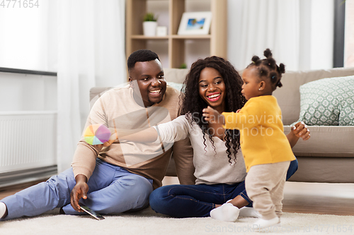 Image of african family playing with baby daughter at home